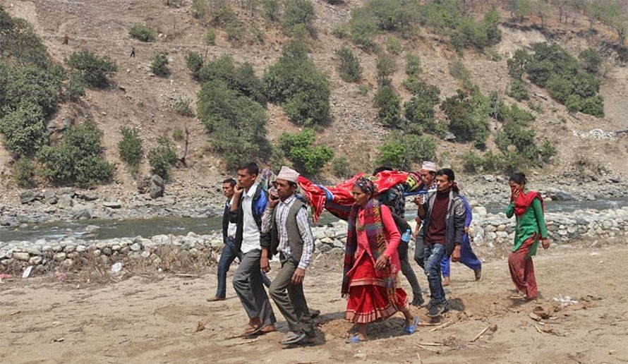 मोटरबाटो नहुँदा सुत्केरीलाई डोकोमा बोक्दै ।